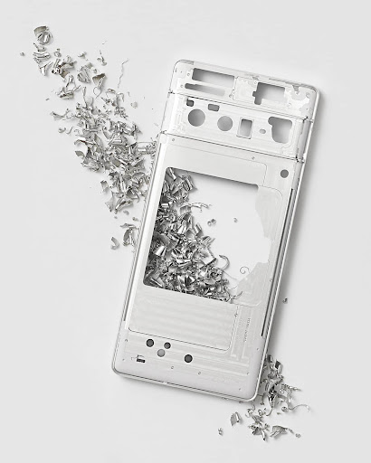 A bare, Pixel phone aluminium body frame surrounded by metal shavings