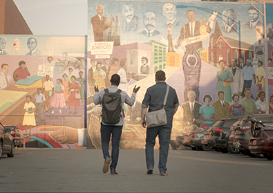 Founders, Justin and Bernard, are walking in front of a mural.