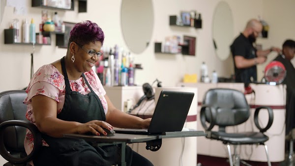 Aspiring IT Support Specialist Melinda Williams takes a Google Certificate Program on a laptop at the salon where she works.