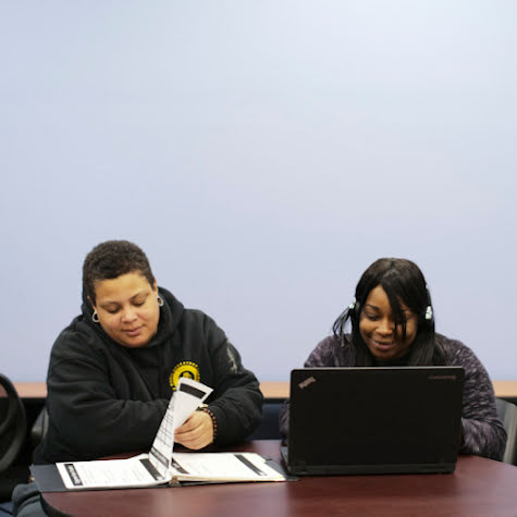 Two young people studying together with a handbook and computer.