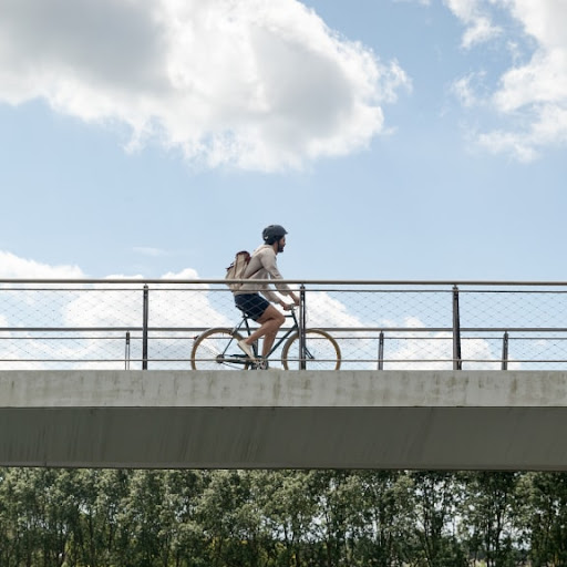 A biker cycles across a bridge on a sunny day.