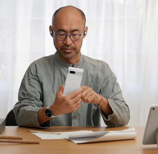 A man using a Google Pixel 7a phone in his office.