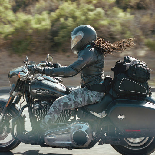 A woman riding her motorcycle with her hair flying in the wind.