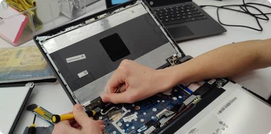 A person works on a deconstructed Chromebook with their hands.