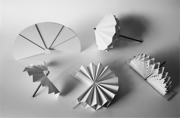 Small scale samples of white deployable shading structure mock-ups on a table.