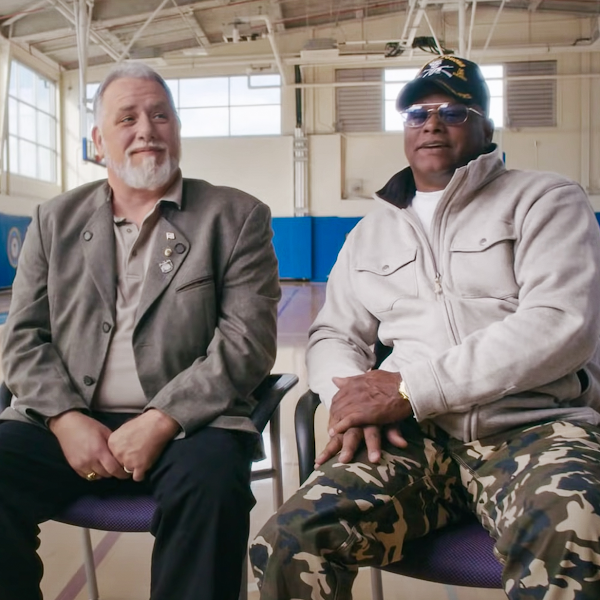 Two veterans sit next to each other while being interviewed in a gymnasium