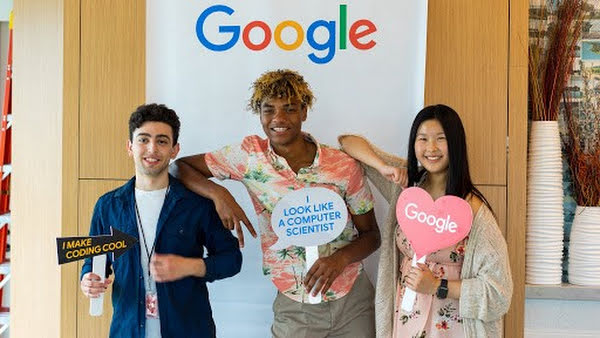 Three students who are learning coding stand in front of the Google logo