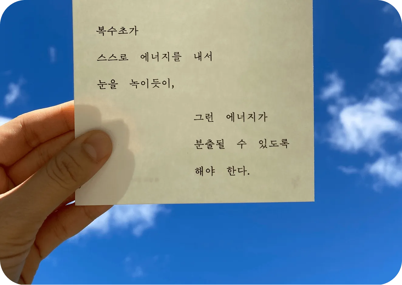 An image of a Lens shopping use case featuring a hand holding a Korean poem on a piece of paper against a blue sky.