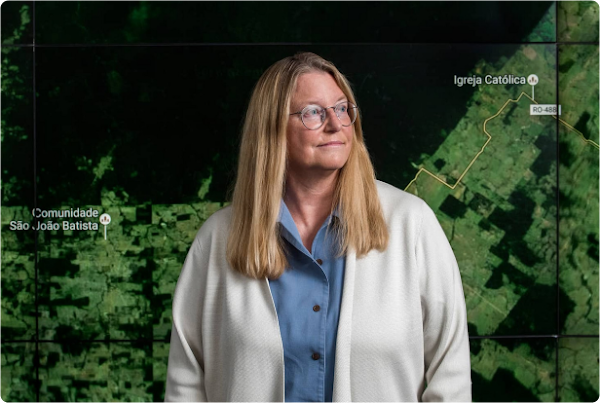 Google engineer, Rebecca Moore, standing in front of a live map of forest loss.
