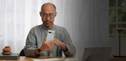A man using a Google Pixel 7a phone in his office.