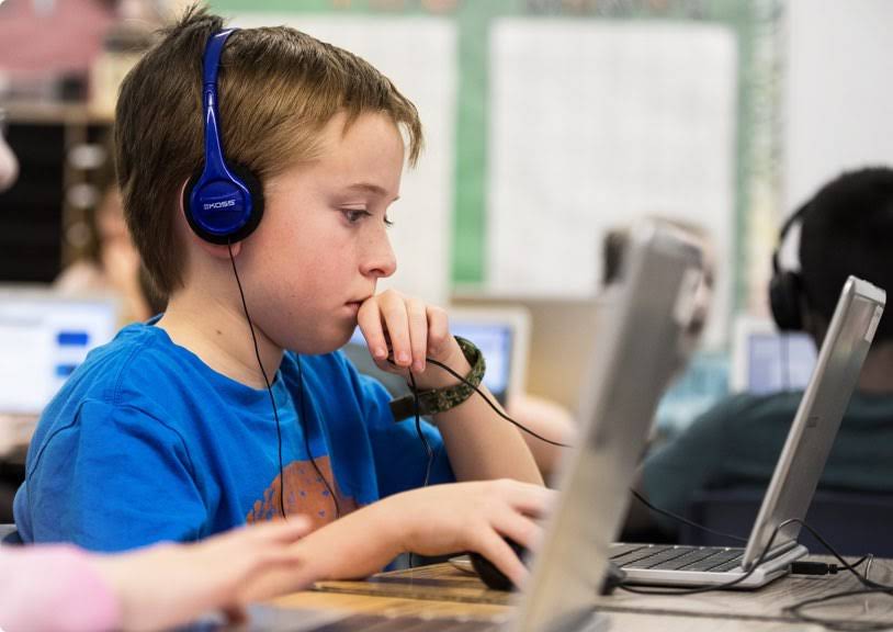 Un niño con auriculares usa un Chromebook.
