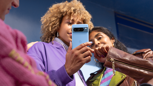 Un groupe de personnes interagissant avec un appareil Pixel 8 Pro bleu.