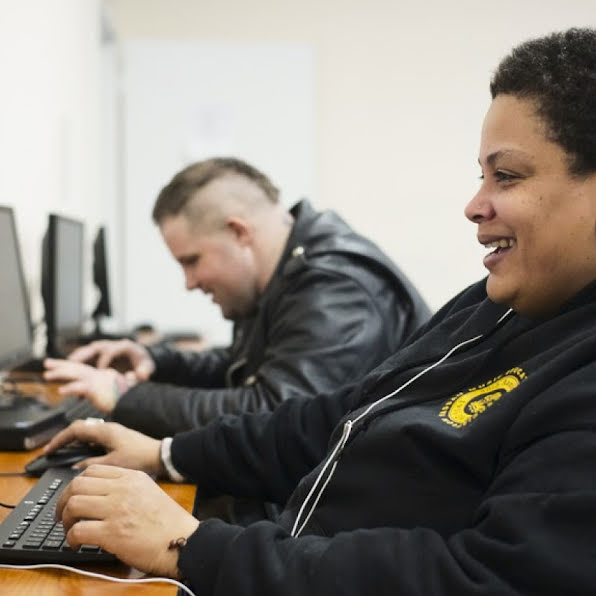 Two young people smiling and working at computers.