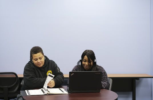 Two young people studying together with a handbook and computer.