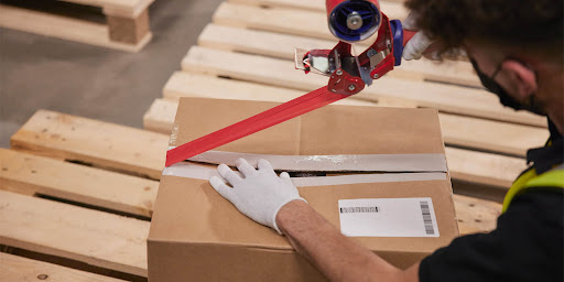 A male worker taping a package 