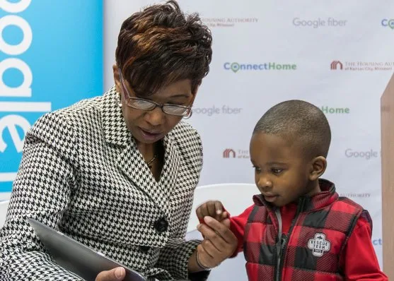 A lady and a child are enjoying content on a tablet using the free internet access provided in public housing by GFIber