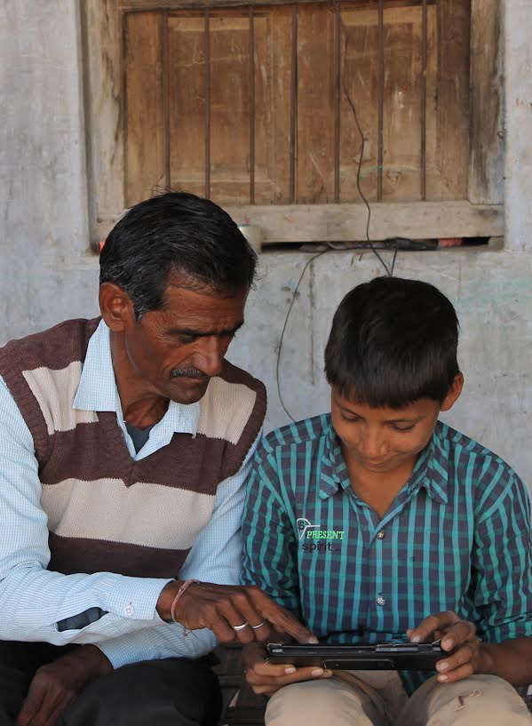Boy and his father working together on a tablet.