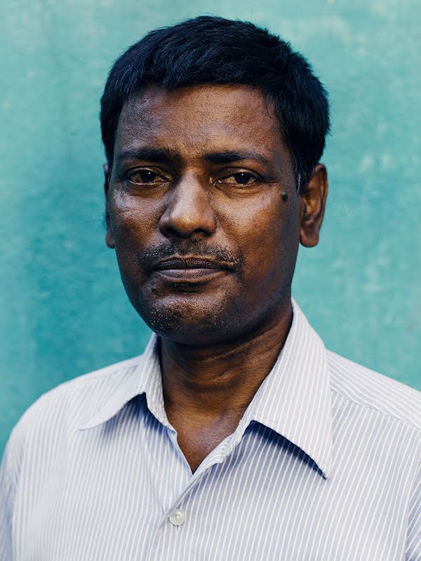 Elumalai, un paciente diabético, mira la cámara con un comportamiento serio. Lleva una camisa y se para frente a una pared azul.
