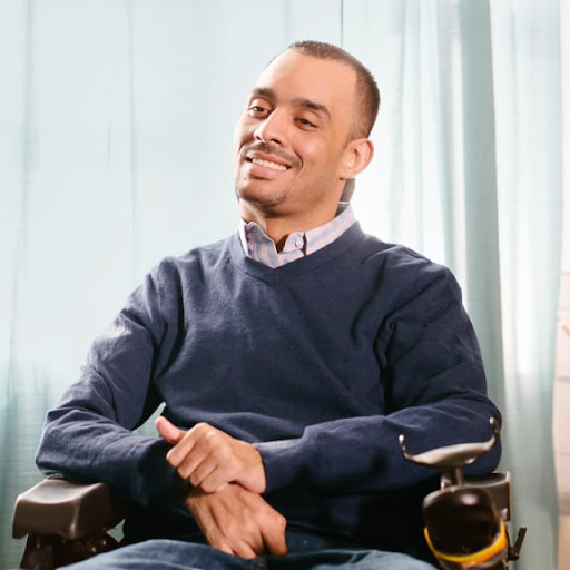 A man with a disability, in a wheelchair, smiling