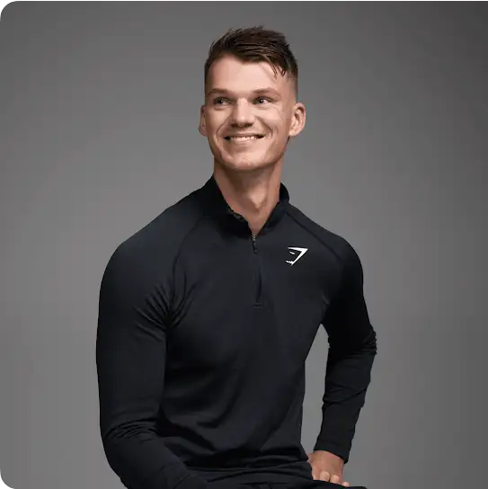 A man smiles broadly while  wearing a long-sleeved Gymshark-branded shirt; before him, a graphic reads, “Nine percent reduction in user drop-offs.”