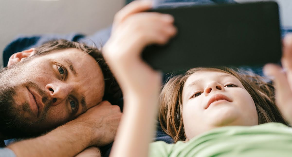 A father and son watch a video on a phone together.