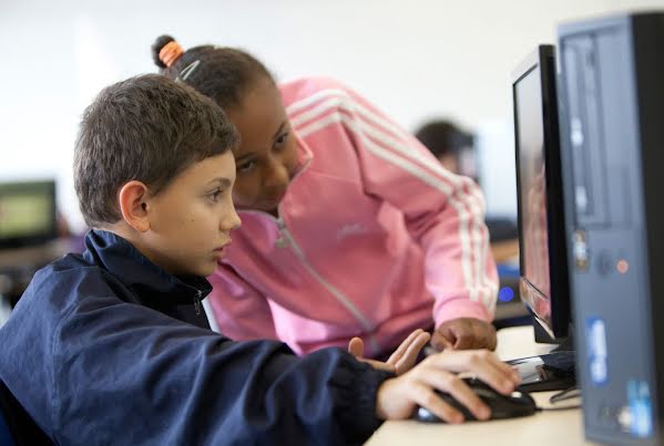 An elementary school boy and girl working together on a computer.