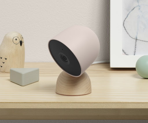 An angled Nest Cam (wired) on a table next to art pieces