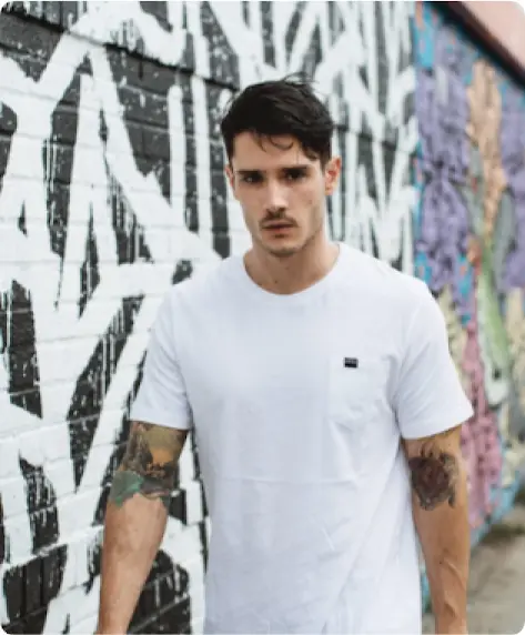 A male model for Diesel.ie walking down the street with graffiti wall in the background.