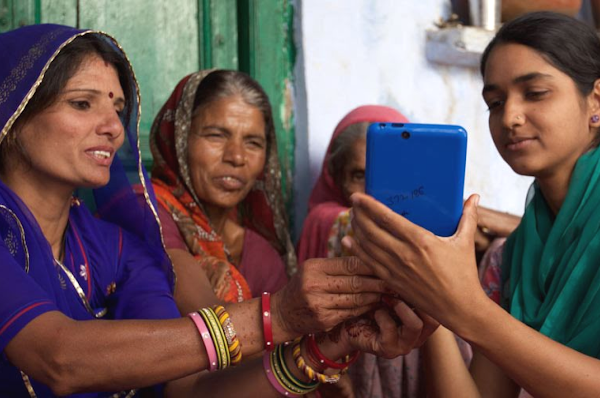 Four Indian women in traditional Indian clothing look at smartphone together