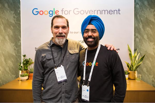 Dos postulantes en una feria laboral de Google para organizaciones gubernamentales con las credenciales del evento.