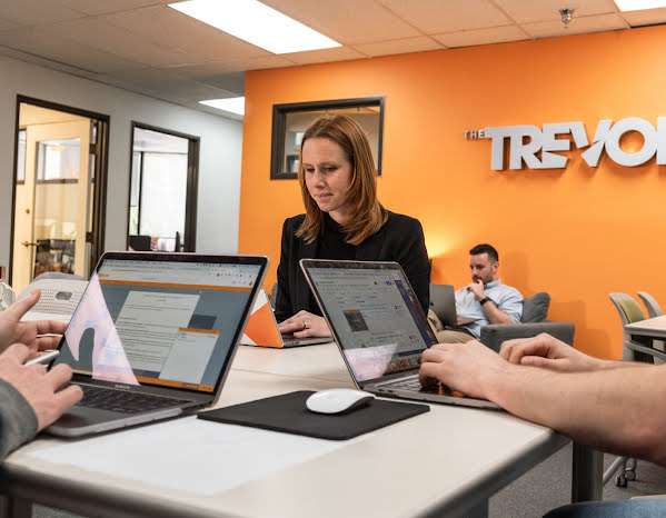 Three people working on laptops at the Trevor Project office.