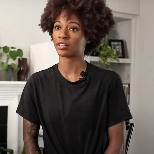 Fotografía cercana de una mujer con afro vestida en una camisa negra