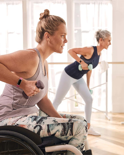 A woman with a disability working out with her friend in a fitness studio