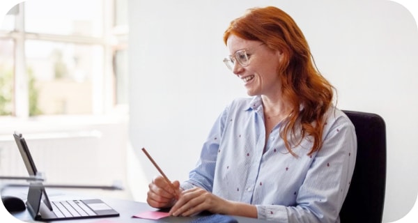 Uma mulher a sorrir e a tirar notas durante uma chamada do Meet 