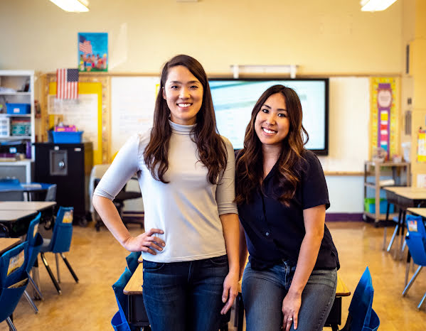 Two young women in a classroom smiling for the camera.