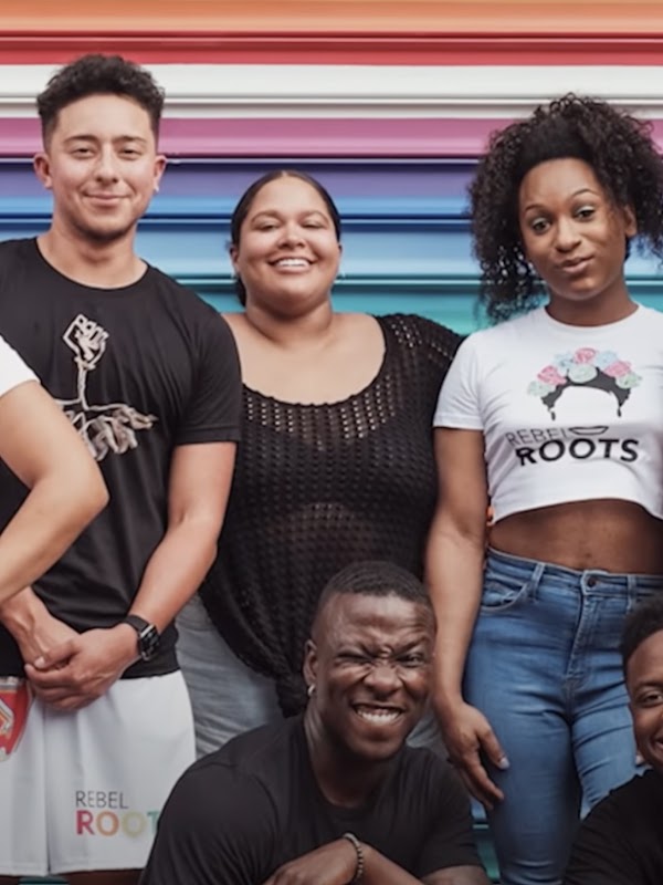 A group of people stand in front of a colorful wall and smile at the camera