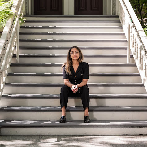 Young woman sitting on steps looking at camera.