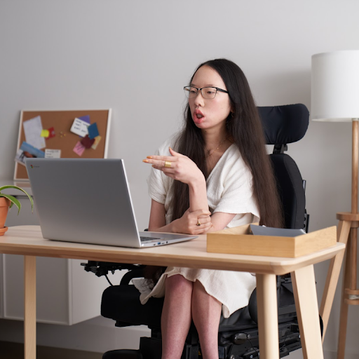 La empleada de Google Aubrie Lee (ella) en su silla de ruedas participando de una reunión en un escritorio