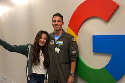 A woman and man, wearing a military uniform, stand in front of a Google sign