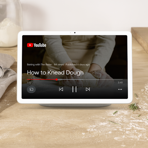 A tablet sits on a charging dock playing a YouTube video titled “How To Knead Dough.”