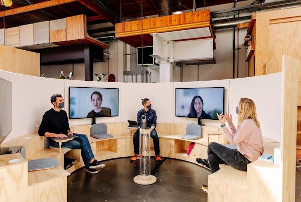 Googler’s meeting in a communal area, where three are in-person and two are working from home and have joined via webcam.