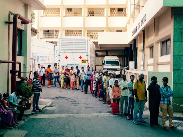 Patients stand in a line outside of Sankara Nethralaya Eye Hospital