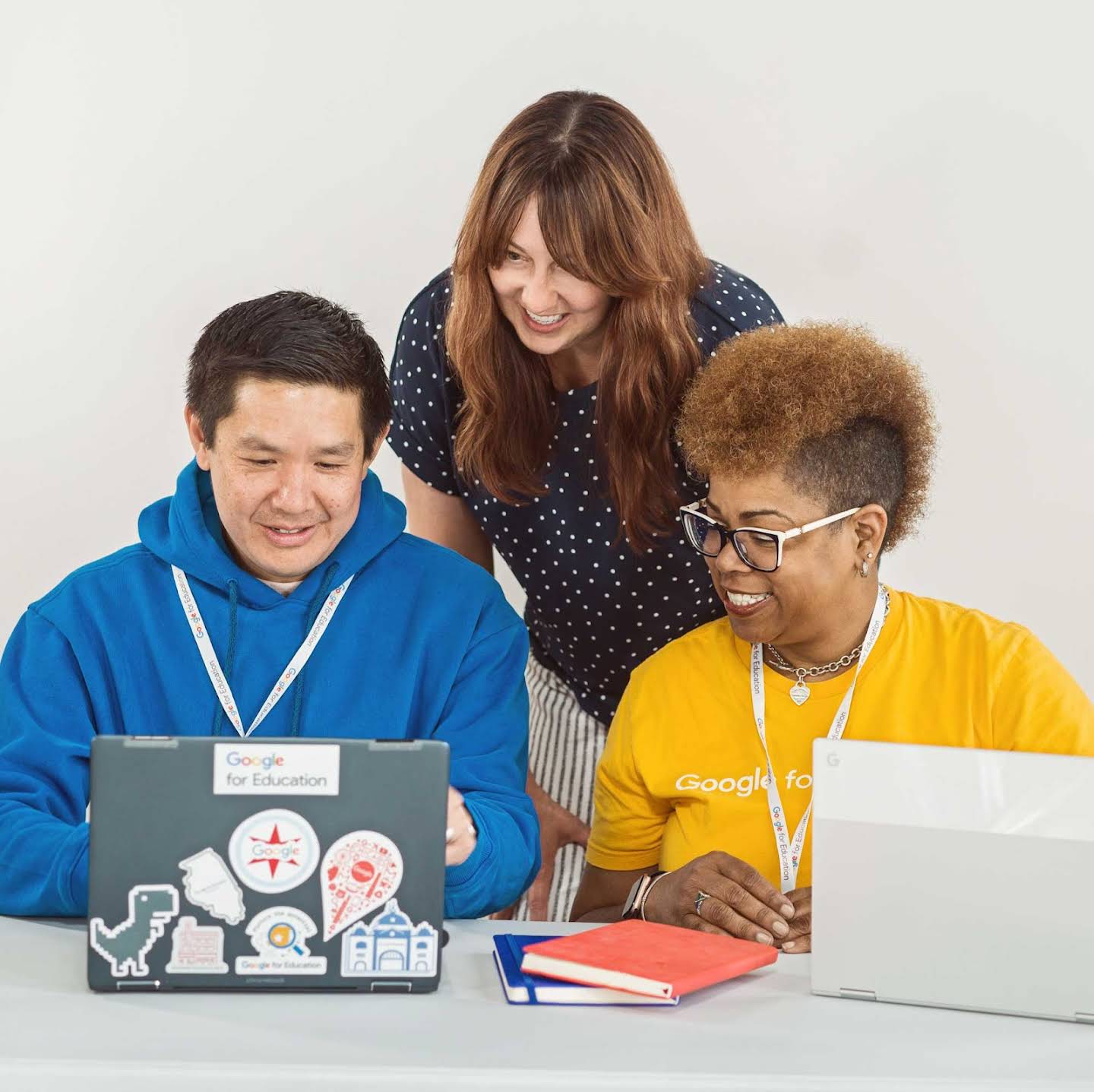 Kuva kolmesta kouluttajasta, jotka tekevät yhteistyötä Chromebookin äärellä