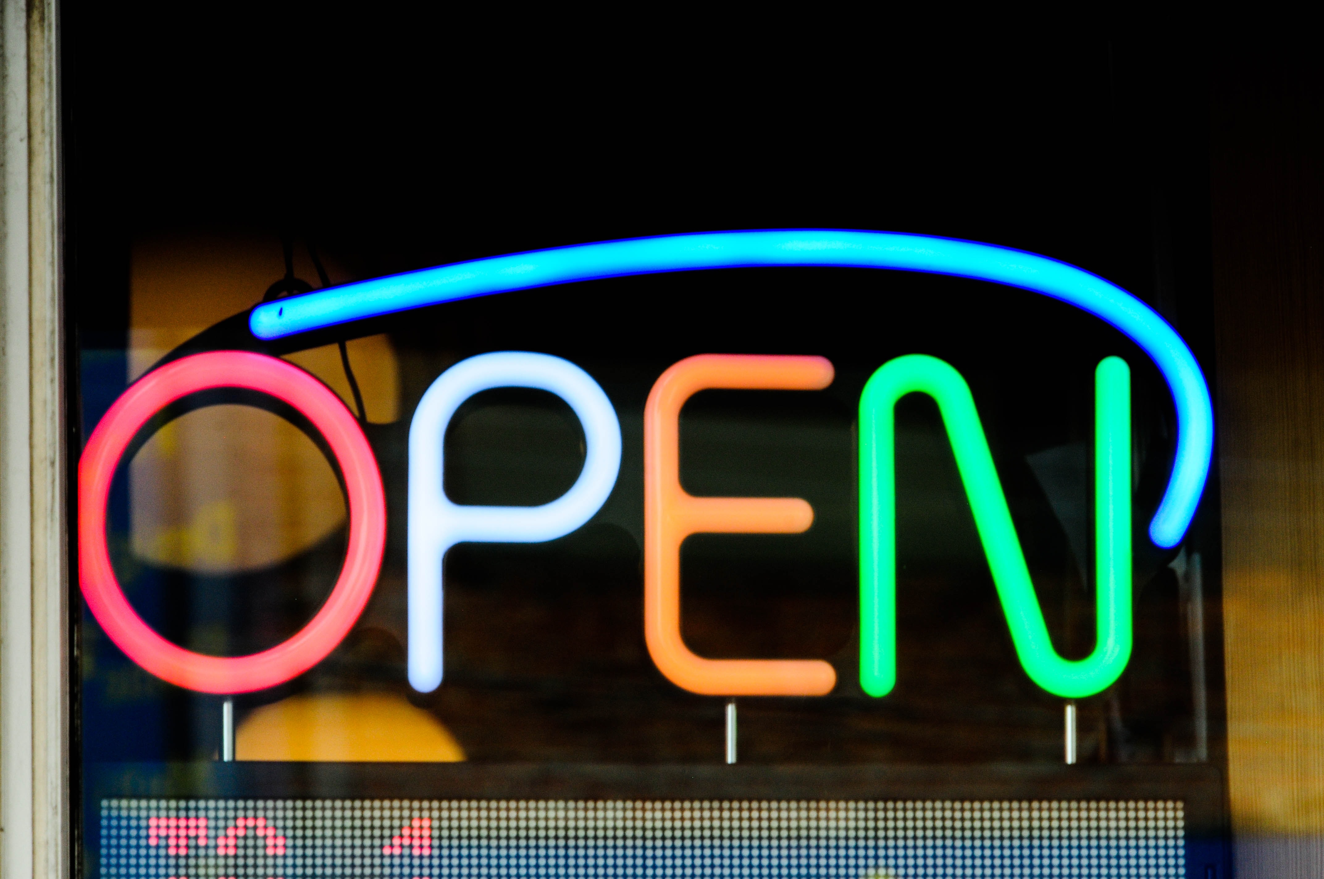 Neon sign in several colours reading 'Open'
