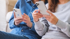 Two people holding smartphones on couch 