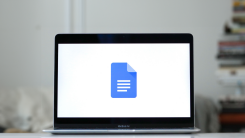 A laptop on a table showing the Google Docs logo