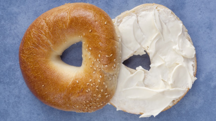 A bagel cut in half with cream cheese in the middle.