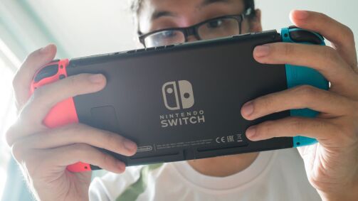 A man looking at a Nintendo Switch, viewed from the back