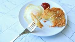 Hash brown and egg on a plate with ketchup.