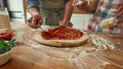 Close-up of hands making pizza at home.